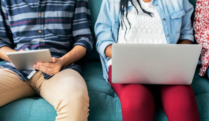 Millennials with tech devices in front of them on a blue bench