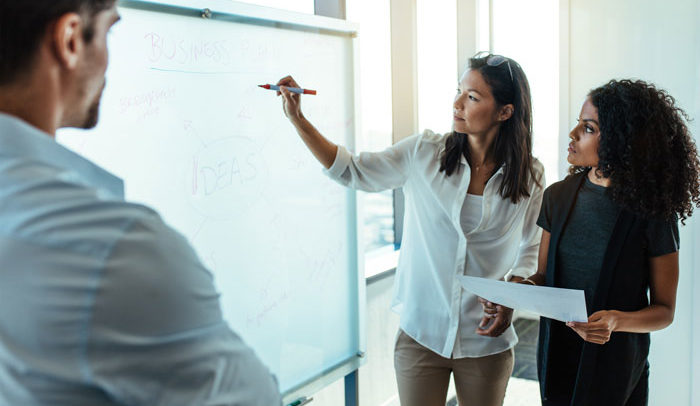 Group of young professions working at a white board calculating effects of group health insurance for their business
