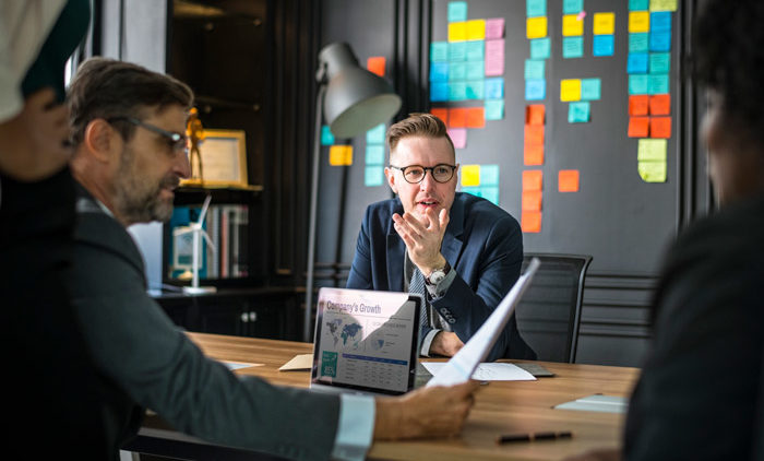 young business man explaining group health insurance options to business group at a table in an office